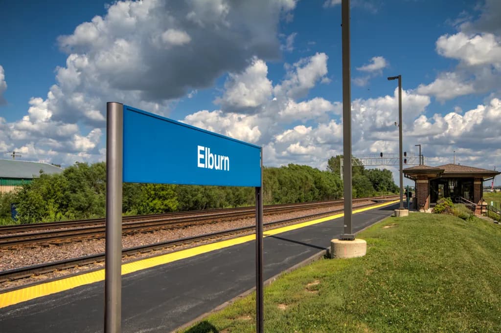 Platform and rail tracks at the Elburn Metra station in Elburn, IL, showing the station building to the right