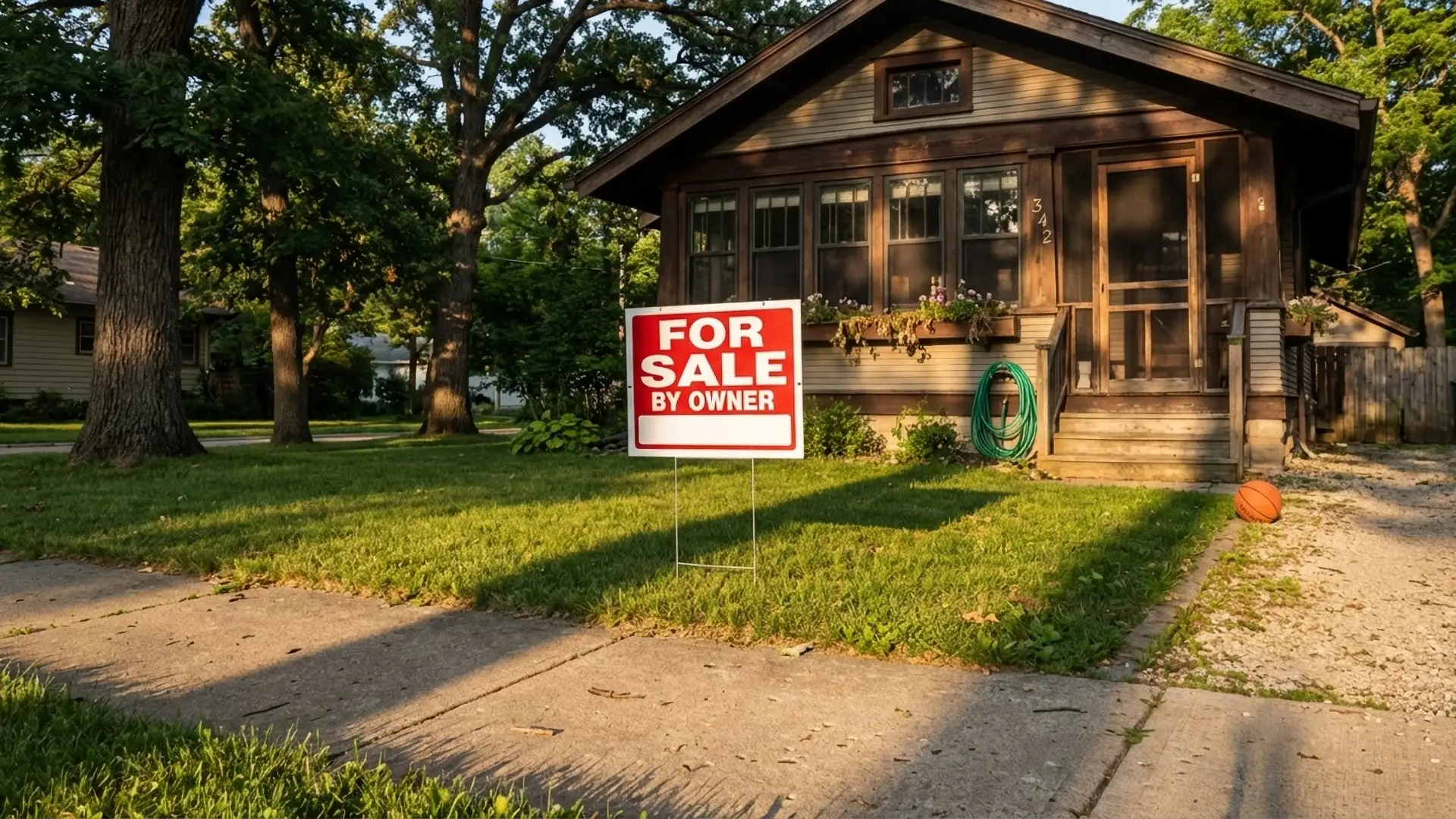 For sale by owner sign in front of a craftsman bungalow at golden hour